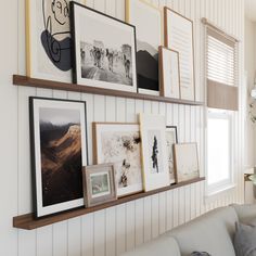 a living room filled with furniture and framed pictures on the wall above a white couch