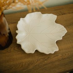 a white plate sitting on top of a wooden table next to a vase with flowers