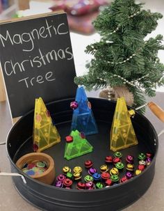 a christmas tree made out of plastic cups and magnets on a tray next to a sign that says magnetic christmas tree