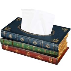 three books stacked on top of each other with a tissue dispenser