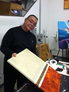 a man standing in front of an easel with paint and paper on the table