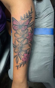 a woman's arm with a butterfly and flowers tattoo on the left side of her leg