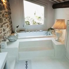 a bathroom with stone walls and flooring next to a bathtub in the corner