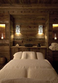 a large bed in a room with wooden walls and lights on the wall above it