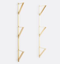 two gold - plated metal shelves are hanging on the wall