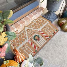 a close up of a door mat on the ground near some plants and pumpkins