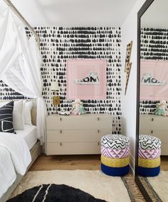 a bedroom with black and white wallpaper, pink mirrors and two stools in front of the bed