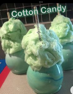 three green cotton candy cones sitting on top of a counter next to a sign that says cotton candy