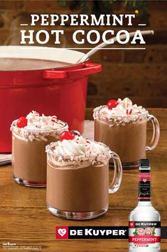 two mugs filled with hot chocolate and whipped cream on top of a wooden table