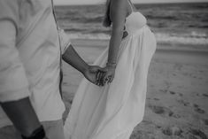 a couple holding hands while walking on the beach