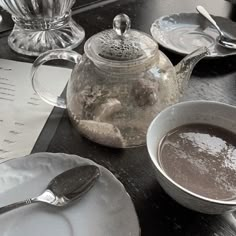 a table topped with plates and cups filled with hot chocolate next to a tea pot