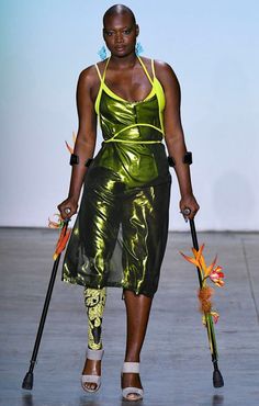 a woman walking down a runway with an umbrella