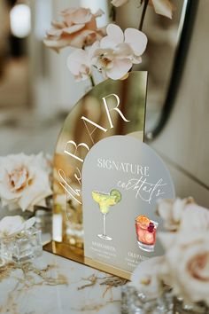 there is a sign that says bar signature cocktails on the table next to some flowers