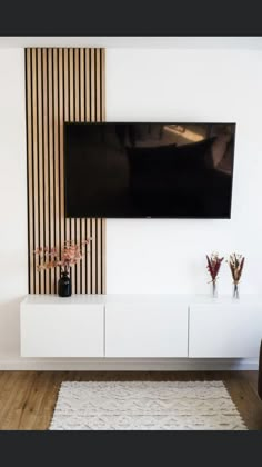 a flat screen tv mounted to the side of a white entertainment center in a living room