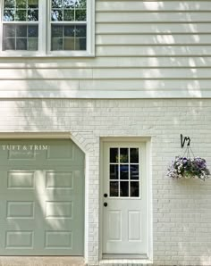 a white brick building with two doors and window boxes on the side of it that says tuff & trim