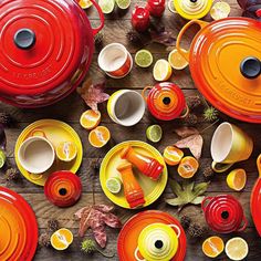 an assortment of red and yellow dishes on a wooden table with autumn leaves around them