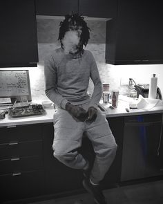 a man with dreadlocks sitting on top of a counter