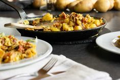 a pan filled with food sitting on top of a table next to plates and utensils