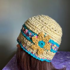 a woman's head wearing a crocheted hat with flowers on the side