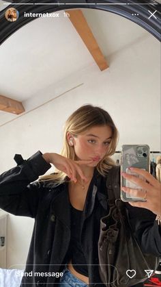 a woman taking a selfie in front of a mirror with her cell phone up to her ear