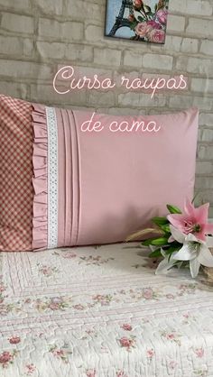 a pink pillow sitting on top of a bed next to a vase with flowers in it