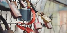 several padlocks attached to a fence with red ribbons hanging from them and locks in the background