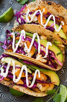 two fish tacos with cole slaw and avocado on a blue plate