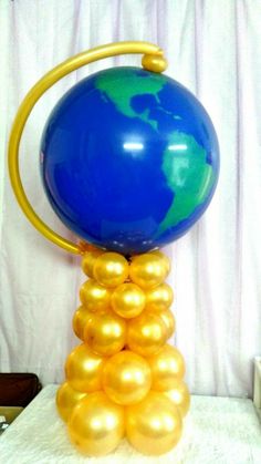 a blue and gold balloon sitting on top of a white table with a globe in the middle