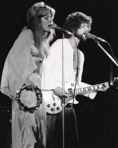 a man and woman singing into microphones on stage