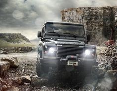 a black land rover is driving through the rocks