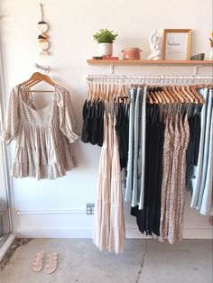 clothes are hanging on the rack in front of a wall mounted shelf with shoes and other items