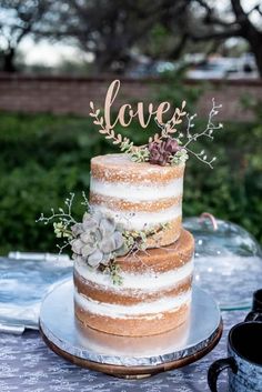 a wedding cake with succulents and the word love on top