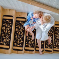 a woman and child laying on top of a bed in a room with wooden paneling