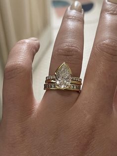 a woman's hand with a ring on it and a pear shaped diamond in the middle