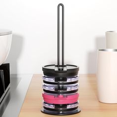 a stack of plastic containers sitting on top of a wooden table next to a microwave