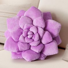 a purple flower pillow sitting on top of a couch