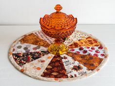 an orange glass jar sitting on top of a patchwork plate