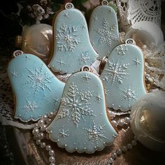 decorated christmas cookies on a platter with pearls and lace around the edges, including snowflakes