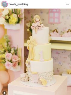 a three tiered cake sitting on top of a white table next to pink and yellow balloons