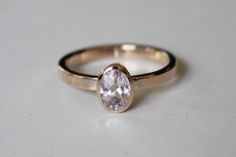 a close up of a gold ring with a white diamond in it on a table