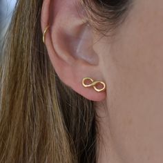 A simple yet elegant design gives this item a unique twist. Each stud earring is crafted of brass wire that was wrapped, soldered and coated with a thick layer of 1-3 Micron 18 karat gold. It's entirely handmade. These gold studs are perfect for your everyday routine. Being so versatile, they will work well for those of you who don't like to change earrings too often.  💛SIZING  ♦Width: 0.47 '' (1.2 cm) ♦Length: 0.2'' (0.5 cm) 💛MATERIALS  ♦ 18K Gold Plated Brass earrings 💛INFO ♦ All our products are nickel-free. ♦ It is recommended to store the jewelry in a dry place. ♦ Oxidized jewelry may get a more silvery tint with time.  ♦ We plate our jewelry with a high-quality 18k gold plating. ♦ To protect the plating over time, you should avoid wearing the jewelry while sleeping, bathing, or pr Gold Infinity Earrings, Tiny Gold Studs, Real Pearl Earrings, Gold Heart Bracelet, Infinity Earrings, Geometric Bracelet, Infinity Jewelry, Bow Bracelet, 18k Gold Earrings