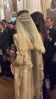 a woman in a wedding dress and veil standing next to a man wearing a suit