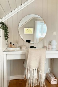 a white dressing table with a mirror on it and a plant in front of it