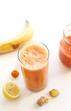 a glass filled with liquid next to a banana and some other food on a table