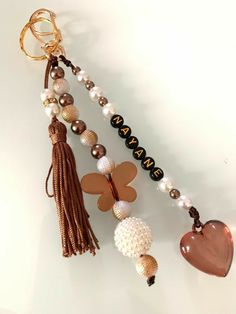 a key chain with beads and charms attached to it on a white surface next to a heart