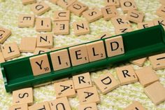 scrabble tiles spelling the word yield on a table with letters scattered around it