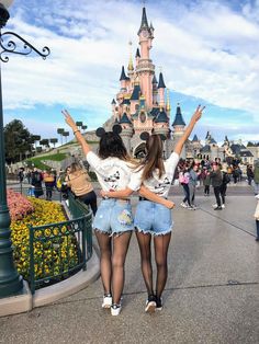 two girls are standing in front of a castle