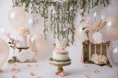 a cake with bunny ears on it sitting in front of some balloons and other decorations