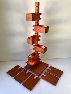 a tall wooden sculpture sitting on top of a white floor next to a light fixture