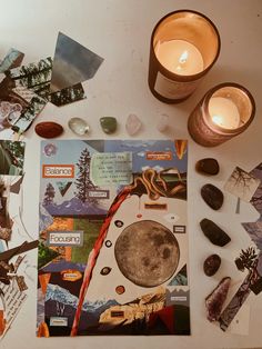 a table topped with pictures and candles next to rocks, paper and other items on top of it